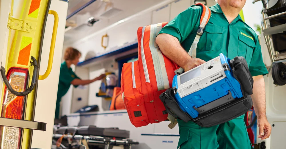 Person exiting an ambulance carrying medical equipment